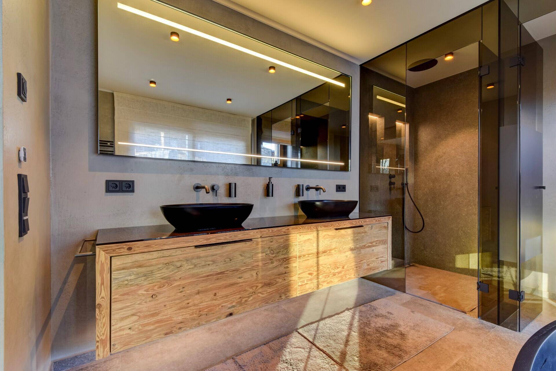 Luxuriöses Badezimmer mit Doppelwaschbecken, großer Dusche und moderner Badewanne.