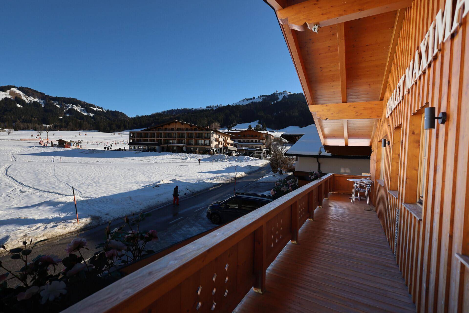 Holzbalkon mit Blick auf die verschneite Landschaft und die umliegenden Gebäude.
