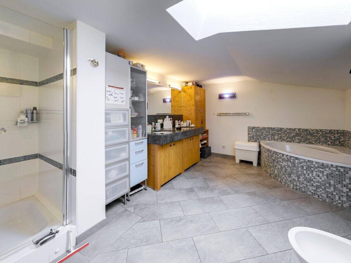 Helles Badezimmer mit Duschkabine, Eckbadewanne mit Mosaikfliesen und Doppelwaschbecken.