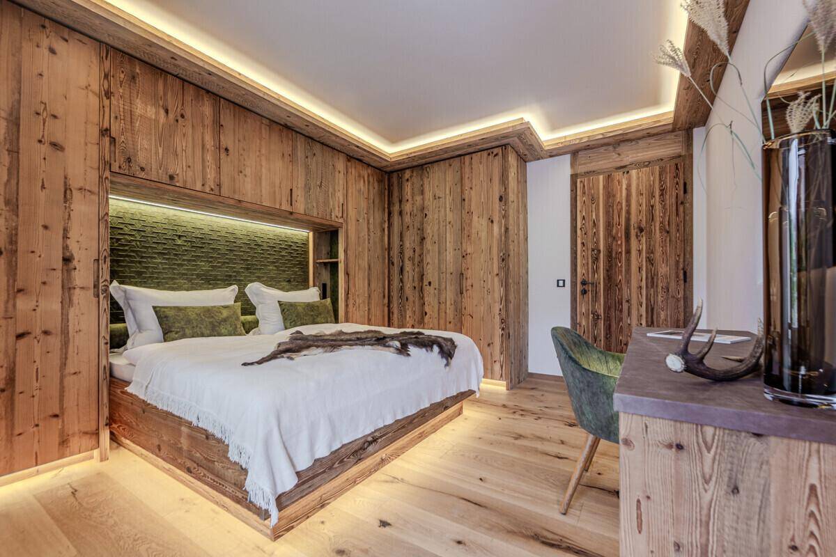 Stilvolles Schlafzimmer mit integrierten Holzschränken, Schreibtisch und indirekter Beleuchtung.