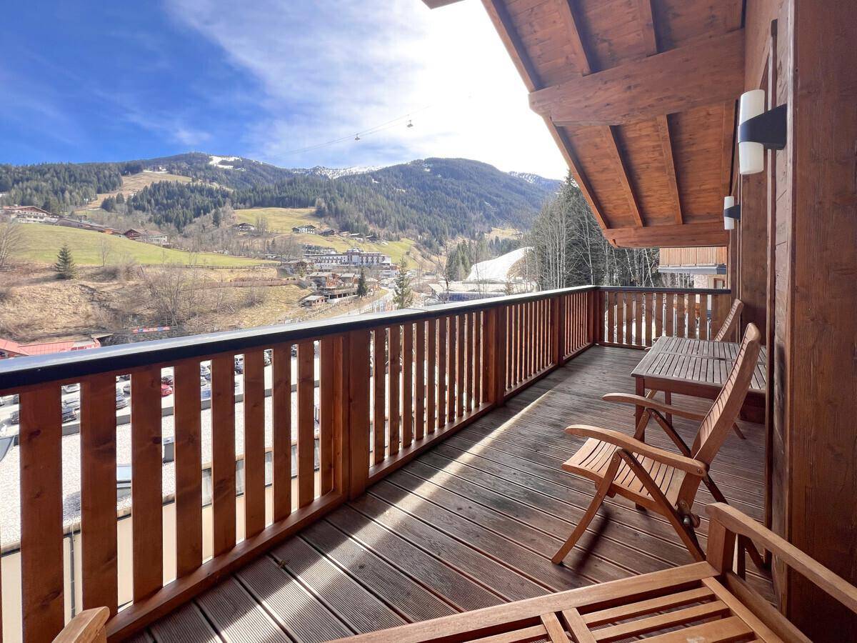 Geräumiger Balkon mit Holzboden und Sitzgelegenheiten, bietet einen weiten Blick auf die Berge.