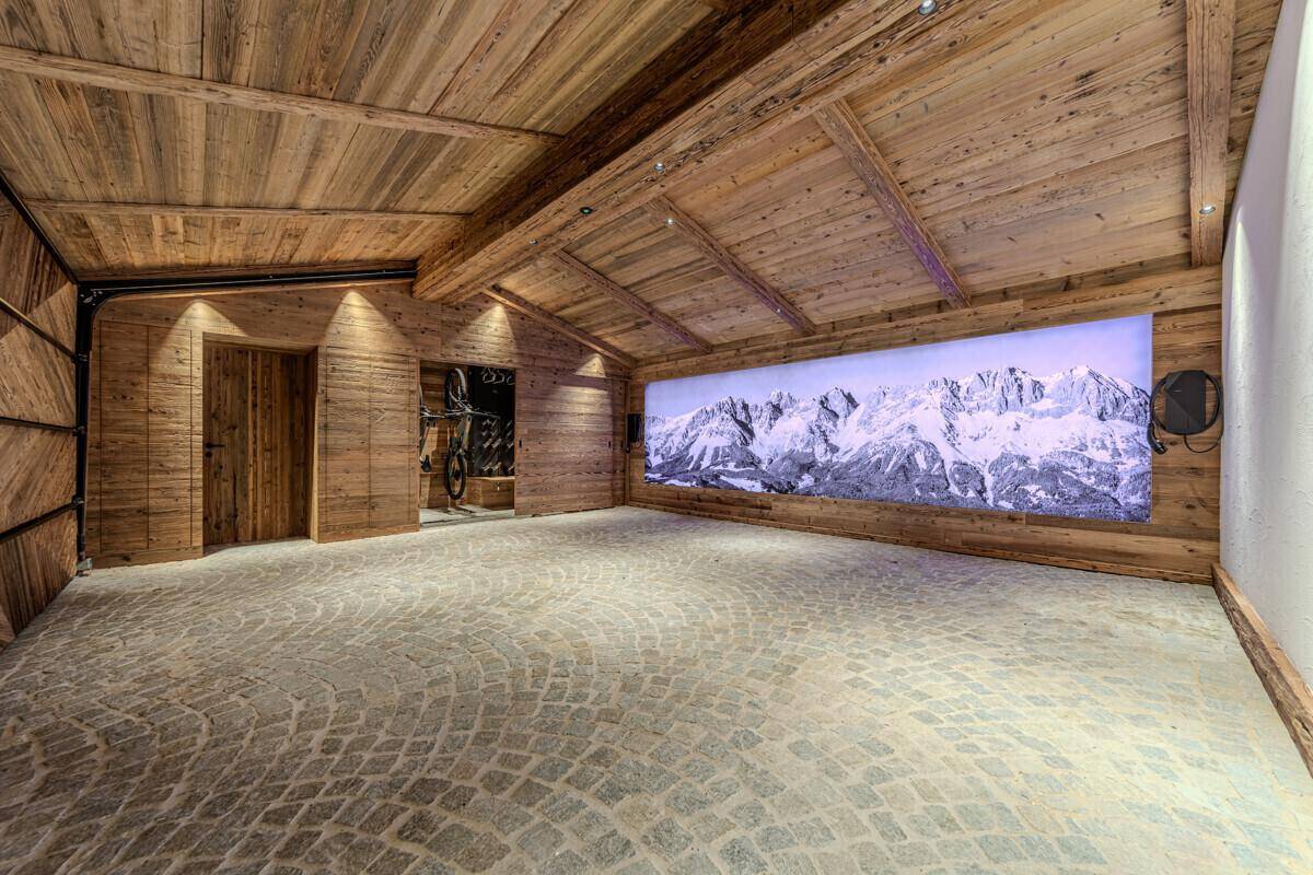 Geräumige Garage mit Holzwänden, Steinboden und großflächiger Berglandschafts-Dekoration.