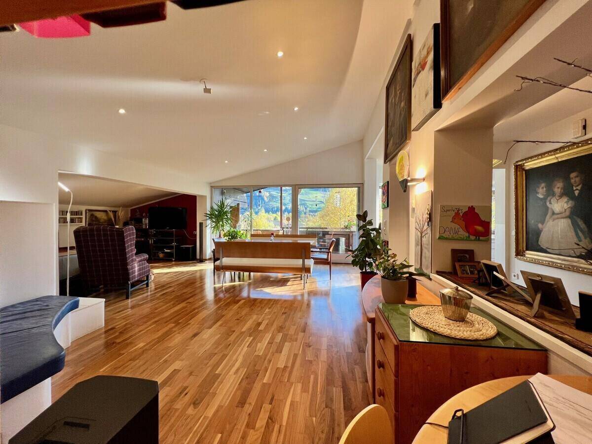 Heller Wohnbereich mit Holzboden, Kunstwerken und weitem Blick in den Essbereich und auf den Balkon.