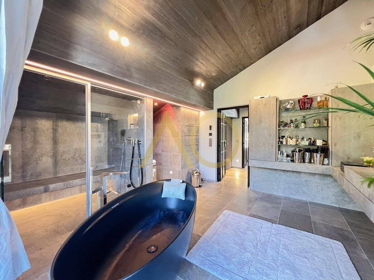 Geräumiges Badezimmer mit freistehender Badewanne, großer Dusche und modernen Armaturen.