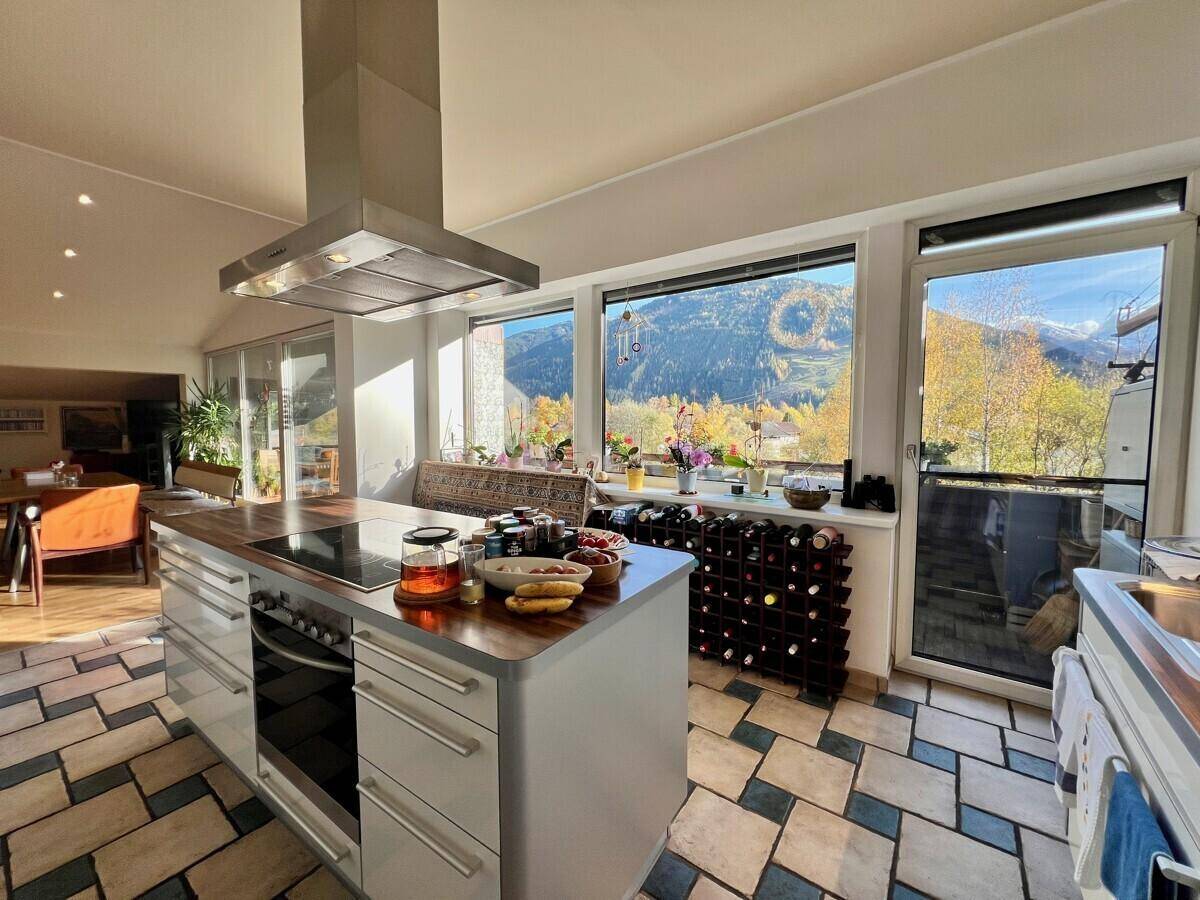 Helle Küche mit Kochinsel, integriertem Ofen und Panoramablick auf die Berge.