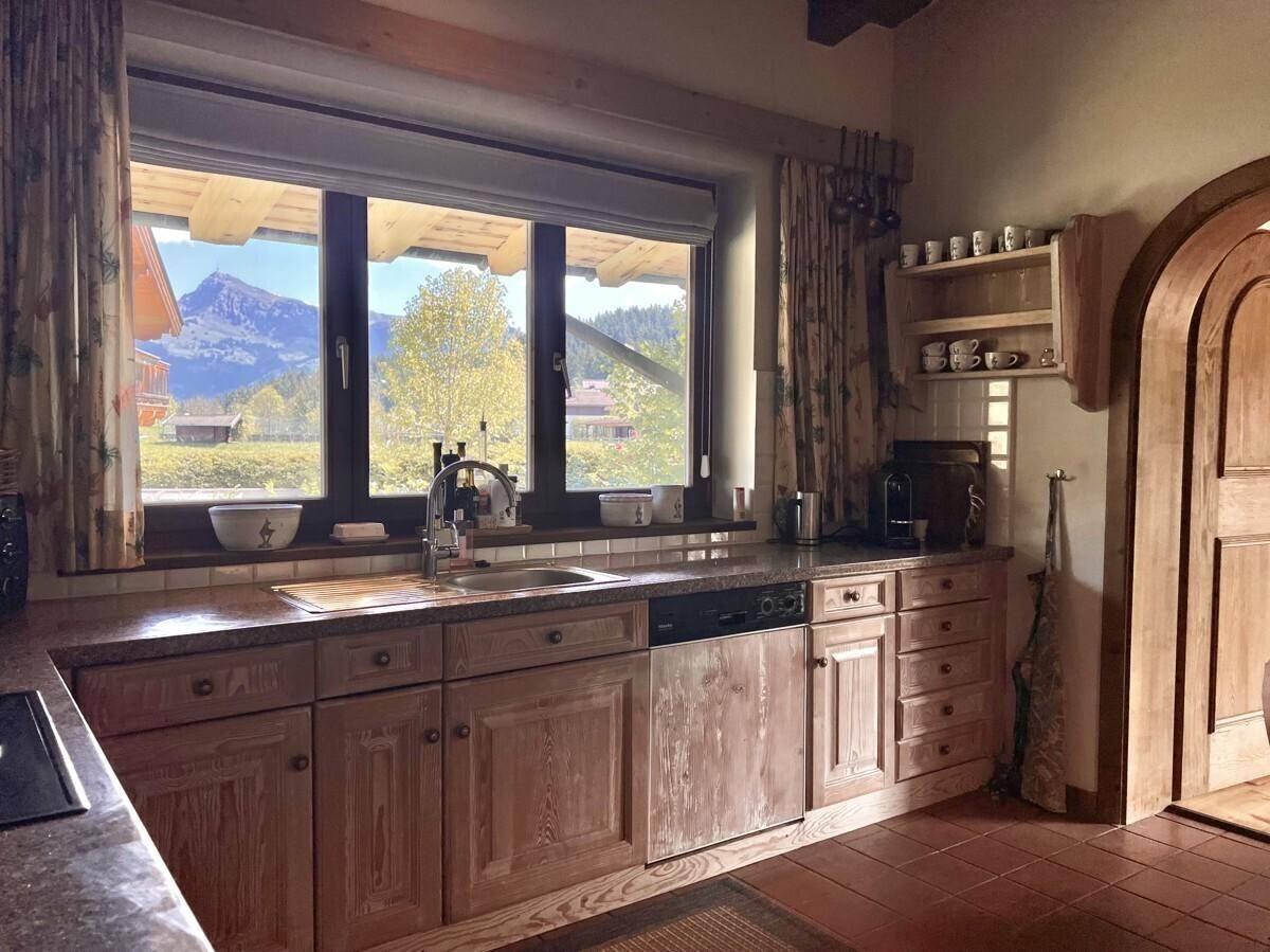 Helle Küche mit Holzeinbauten, Granitarbeitsplatte und einem Fenster mit Bergblick.