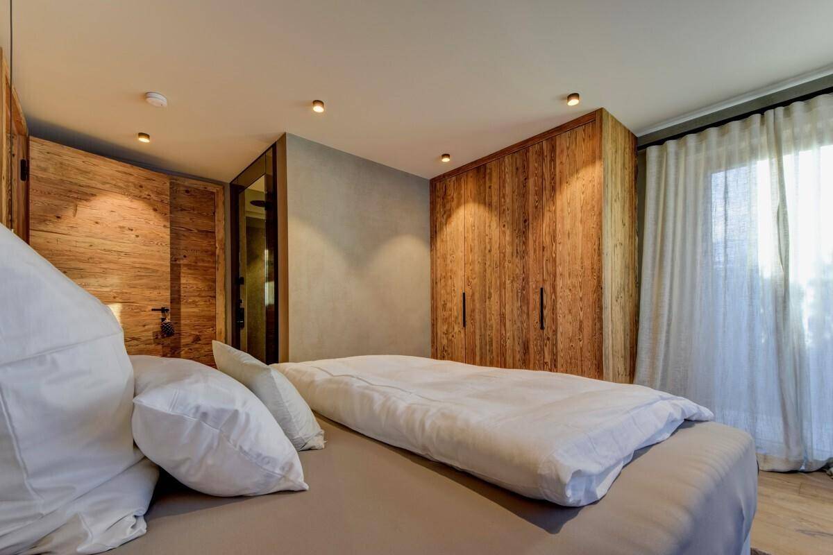 Helles Schlafzimmer mit Holzwänden, Einbauschränken und Zugang zum Außenbereich.