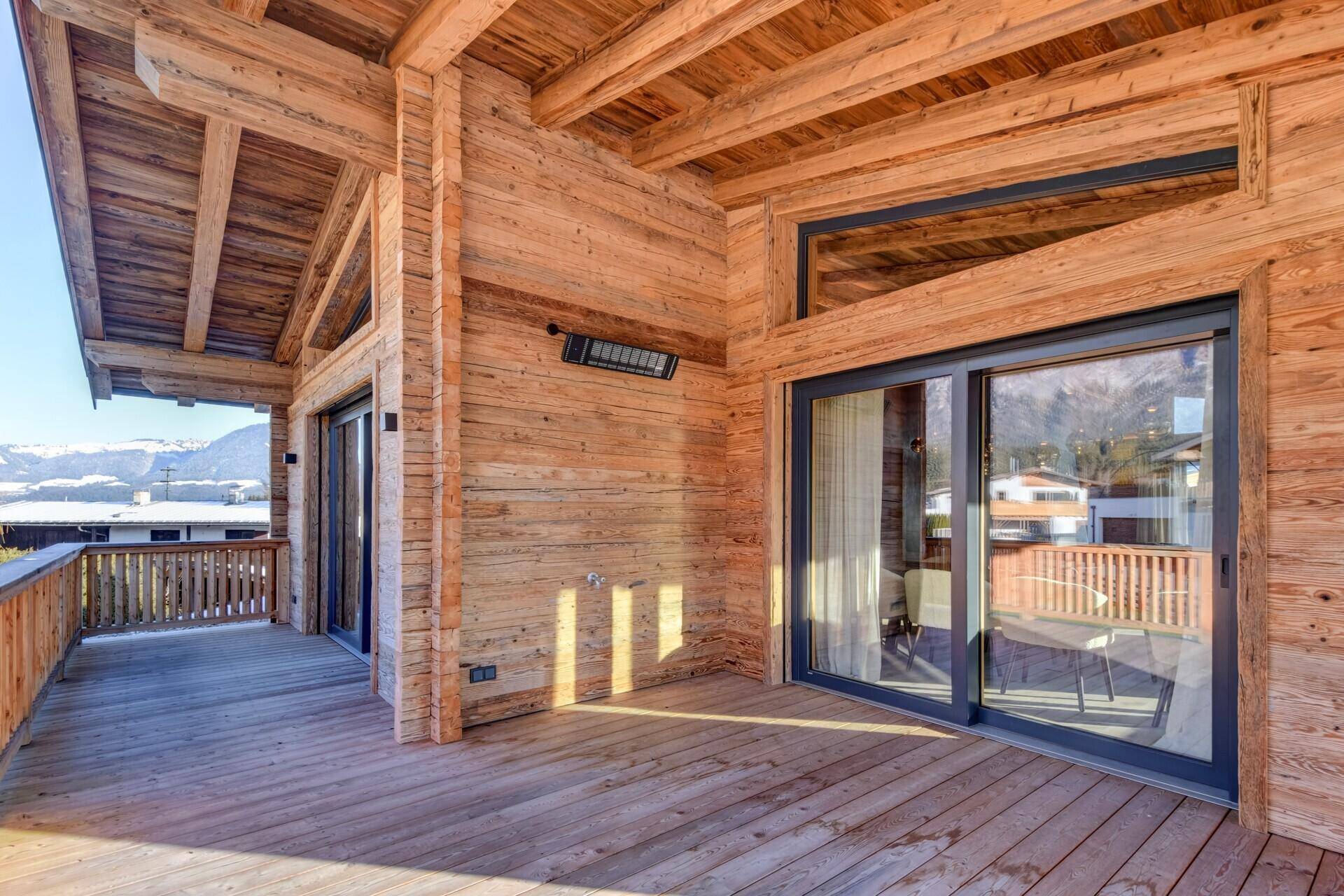 Geräumiger Holzbalkon mit Schiebetüren und Bergblick, ideal für sonnige Tage und frische Luft.