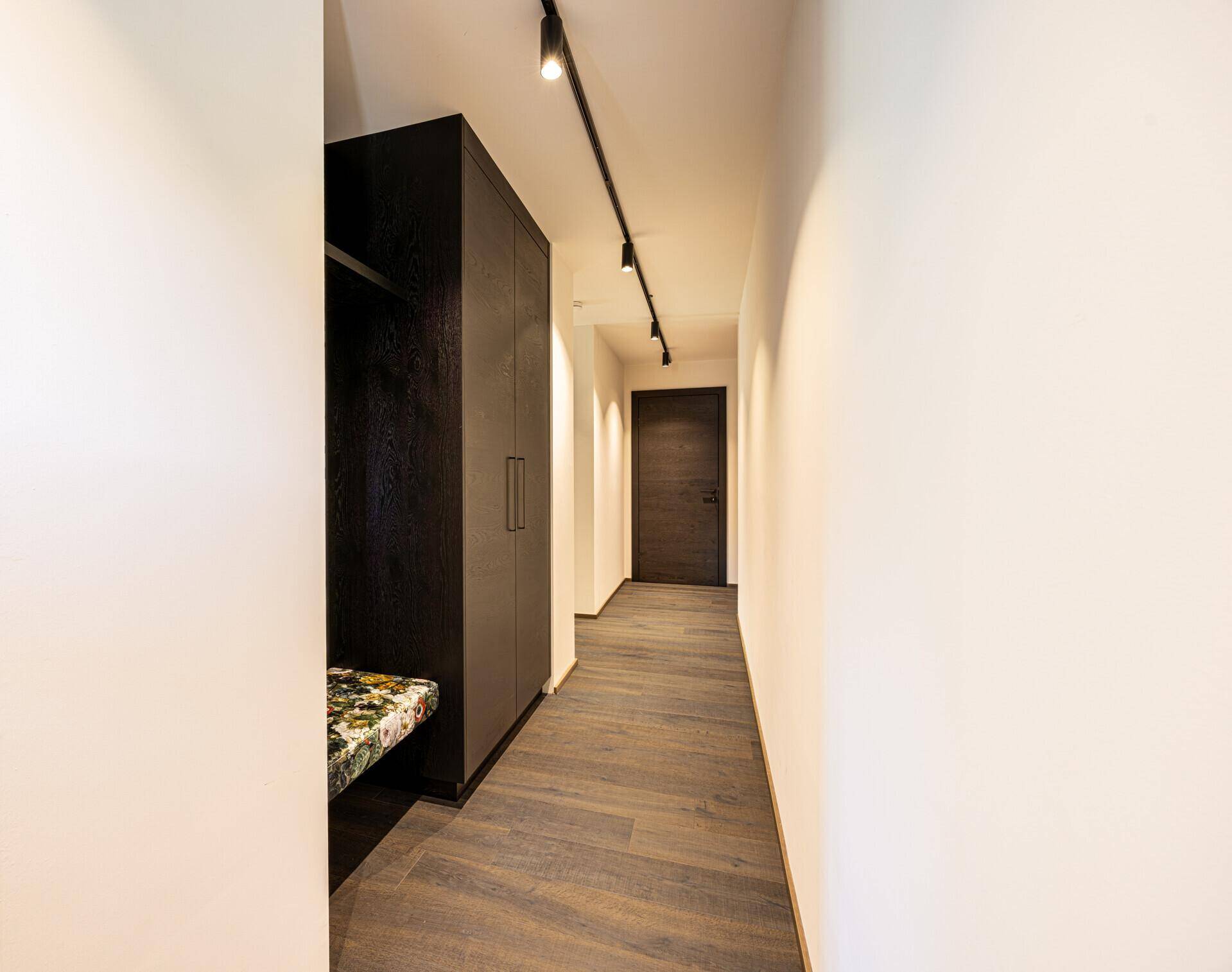 Heller Flur mit Holzboden und integriertem Schrank, der zu weiteren Räumen führt.