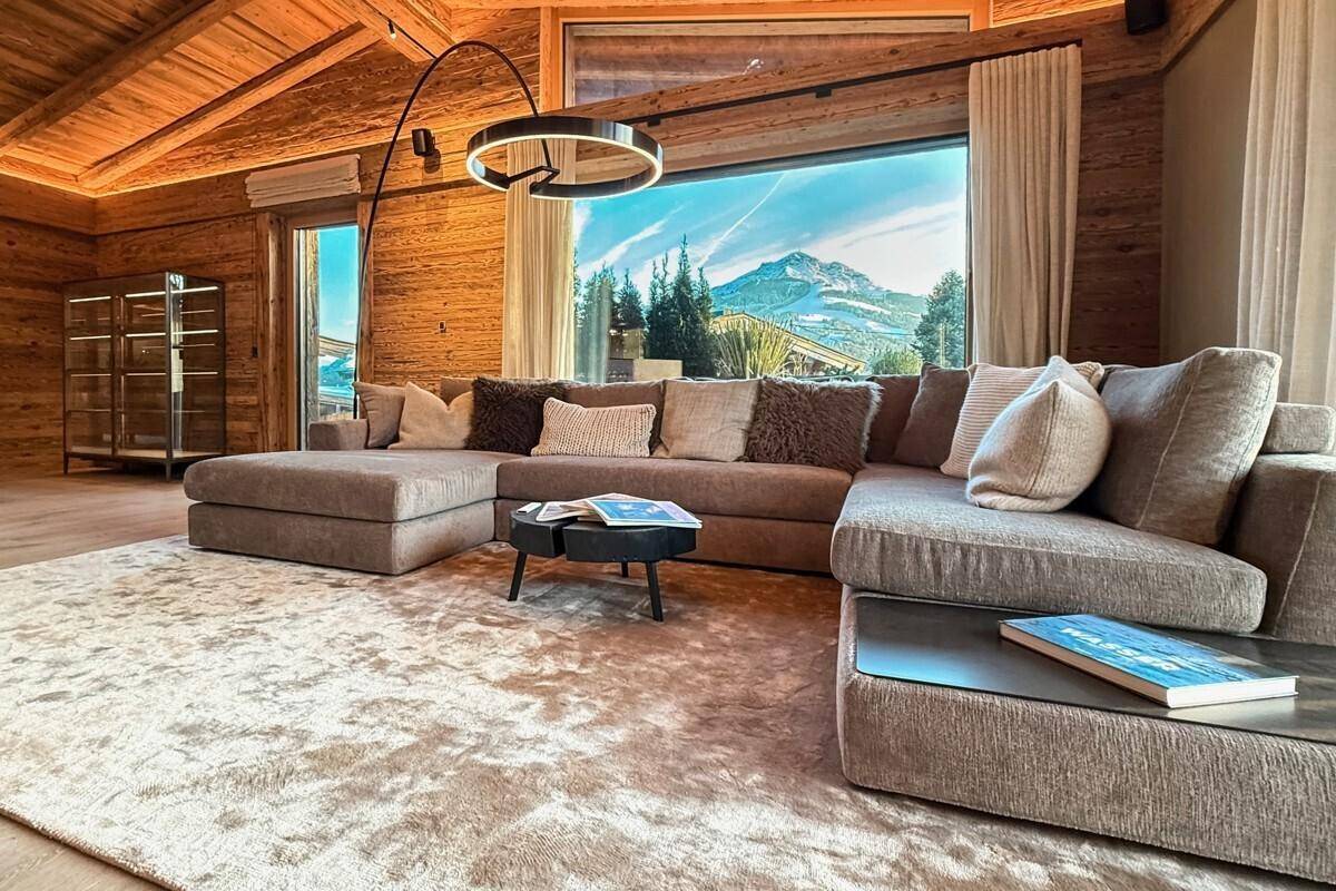 Gemütliches Wohnzimmer mit großem Sofa, Teppich und Panoramablick auf die Berge.