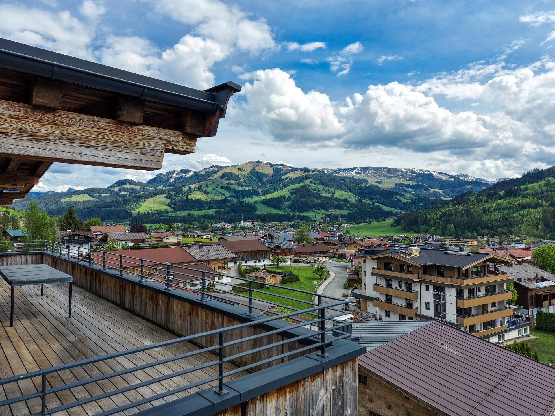 Große Holzterrasse mit Esstisch und weitem Blick über das Tal und die Berge.