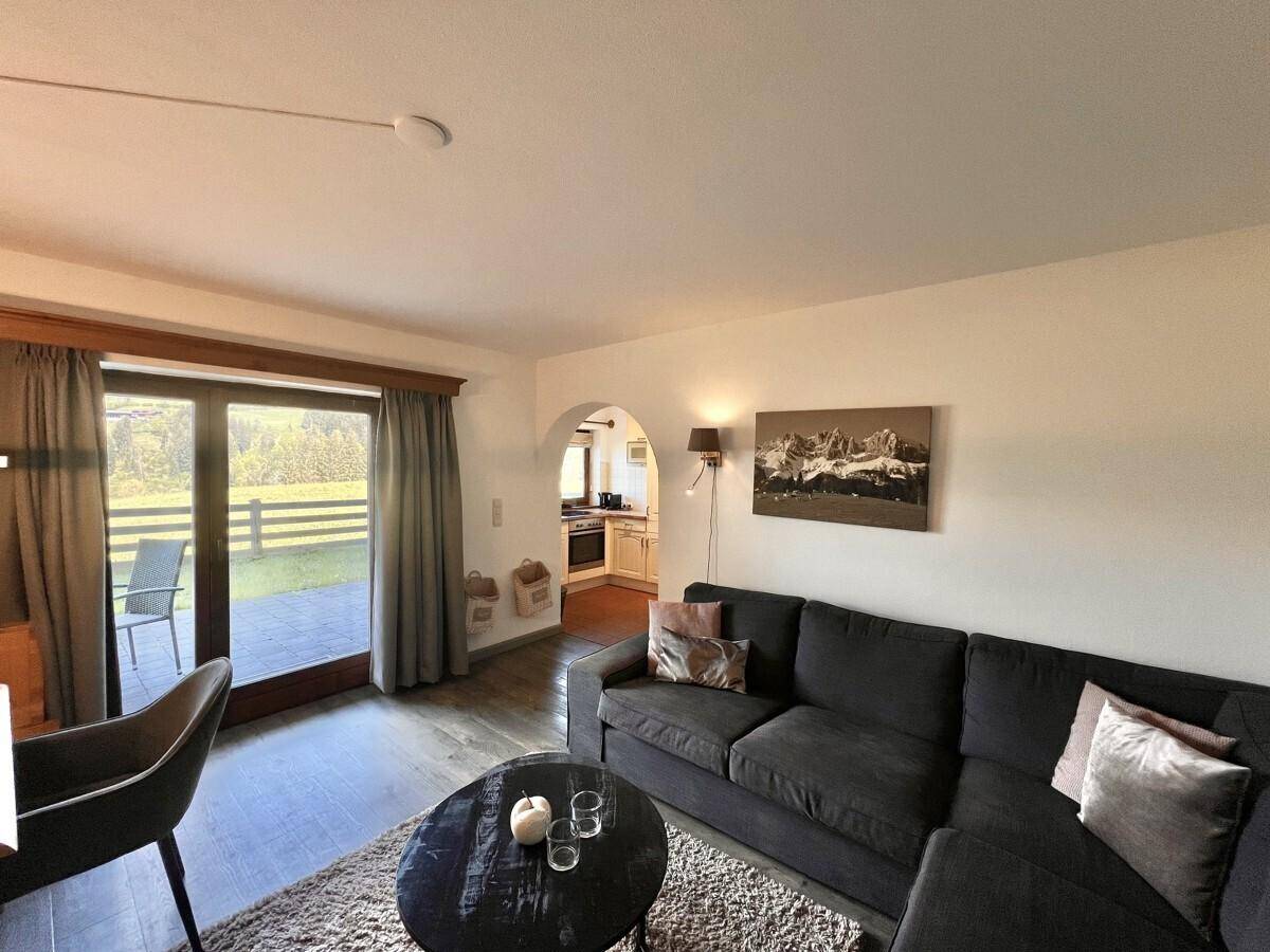 Helles Wohnzimmer mit großem Sofa und direktem Zugang zur Außenterrasse.