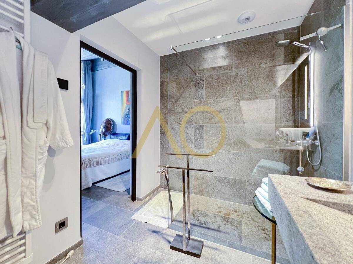 Modernes Badezimmer mit großer begehbarer Dusche und direktem Zugang zum Schlafzimmer.
