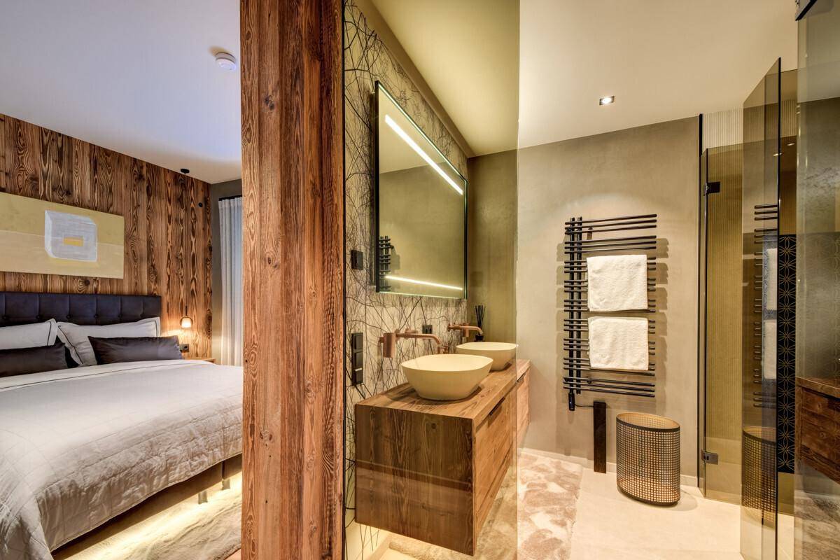 Luxuriöses Badezimmer mit Doppelwaschbecken, begehbarer Dusche und Zugang zum Schlafzimmer.