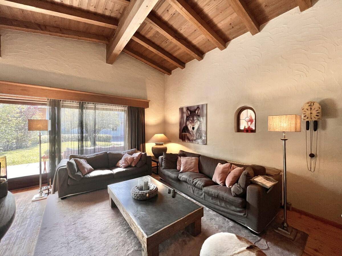 Gemütliches Wohnzimmer mit Kamin, bequemen Sofas und Holzbalkendecke.