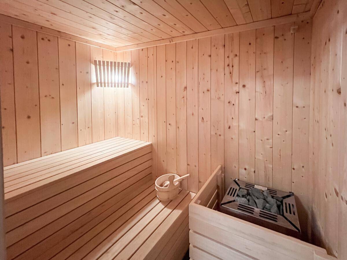Holzvertäfelte Sauna mit Bänken und Saunaofen, bereit für entspannende Momente.