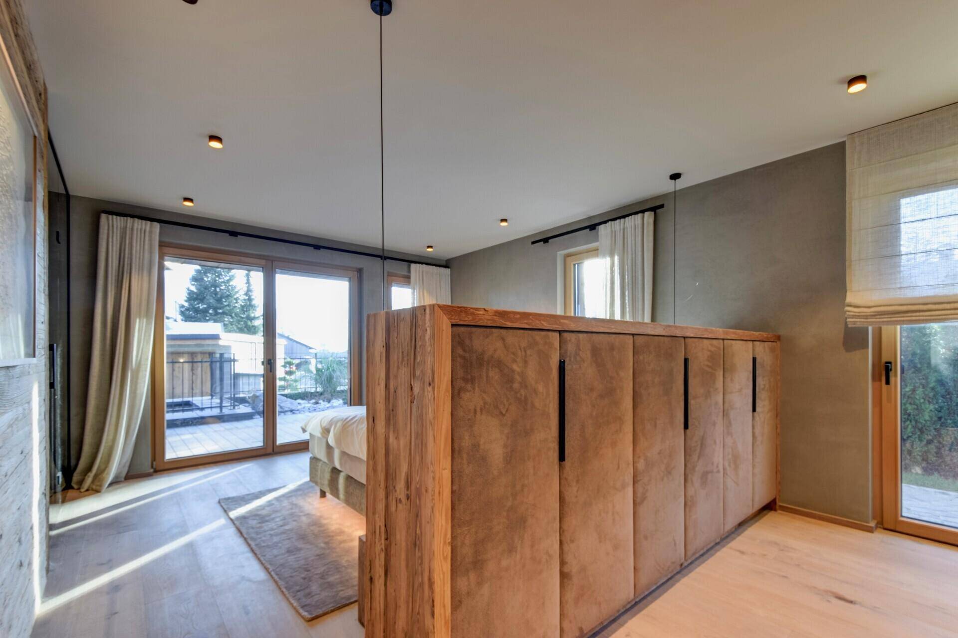 Helles Schlafzimmer mit integrierten Schränken und Zugang zum Balkon, modern eingerichtet.