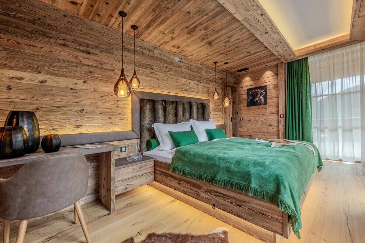 Stilvolles Schlafzimmer mit Holzwänden, Schreibtisch und indirekter Beleuchtung für eine gemütliche Atmosphäre.