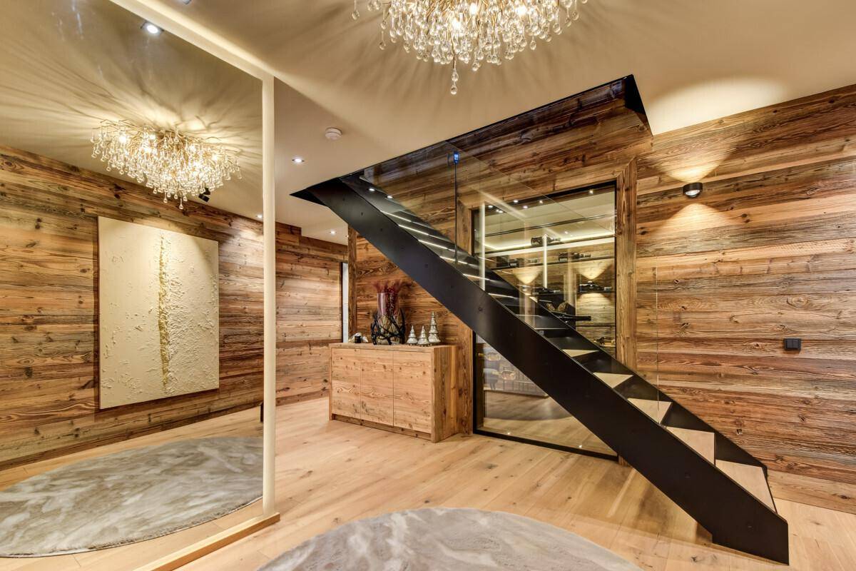Heller Flur mit moderner Treppe, Glasgeländer und integriertem Weinkeller.