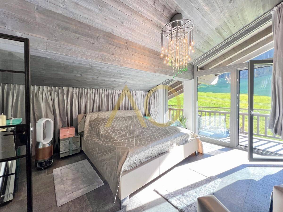 Helles Schlafzimmer mit Holzbalkendecke, Balkonzugang und Blick ins Grüne.