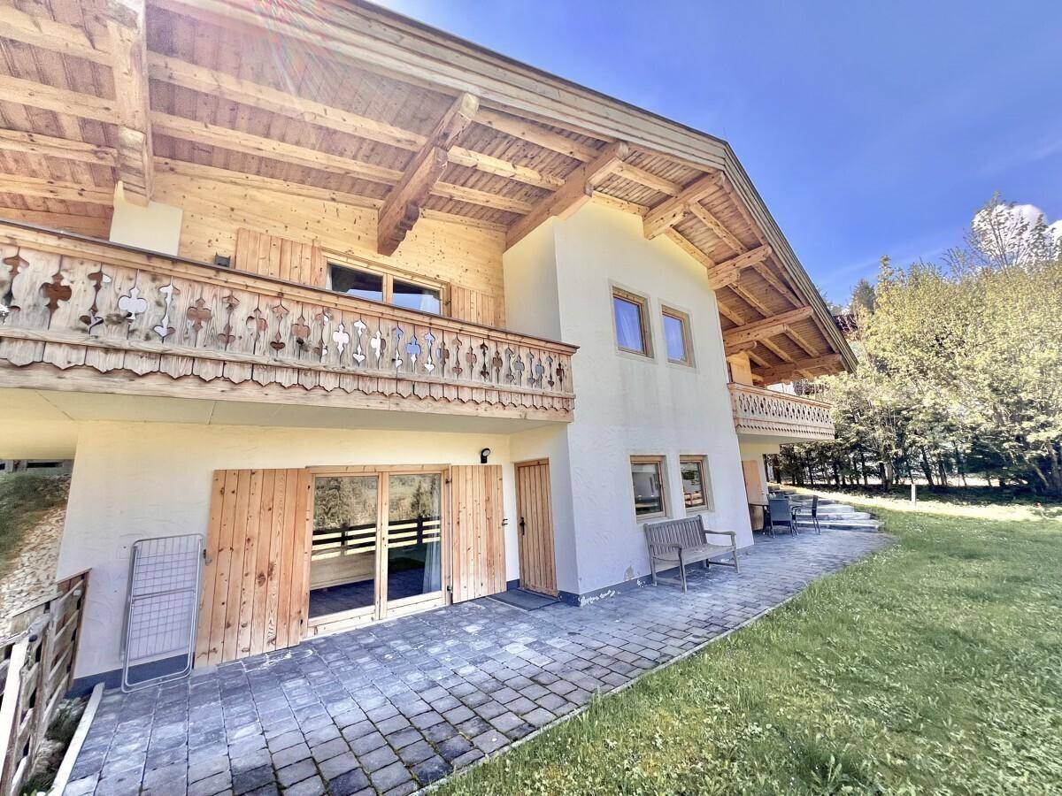 Traditionelle Holzfassade des Hauses mit Balkonen und einer Terrasse im Erdgeschoss.