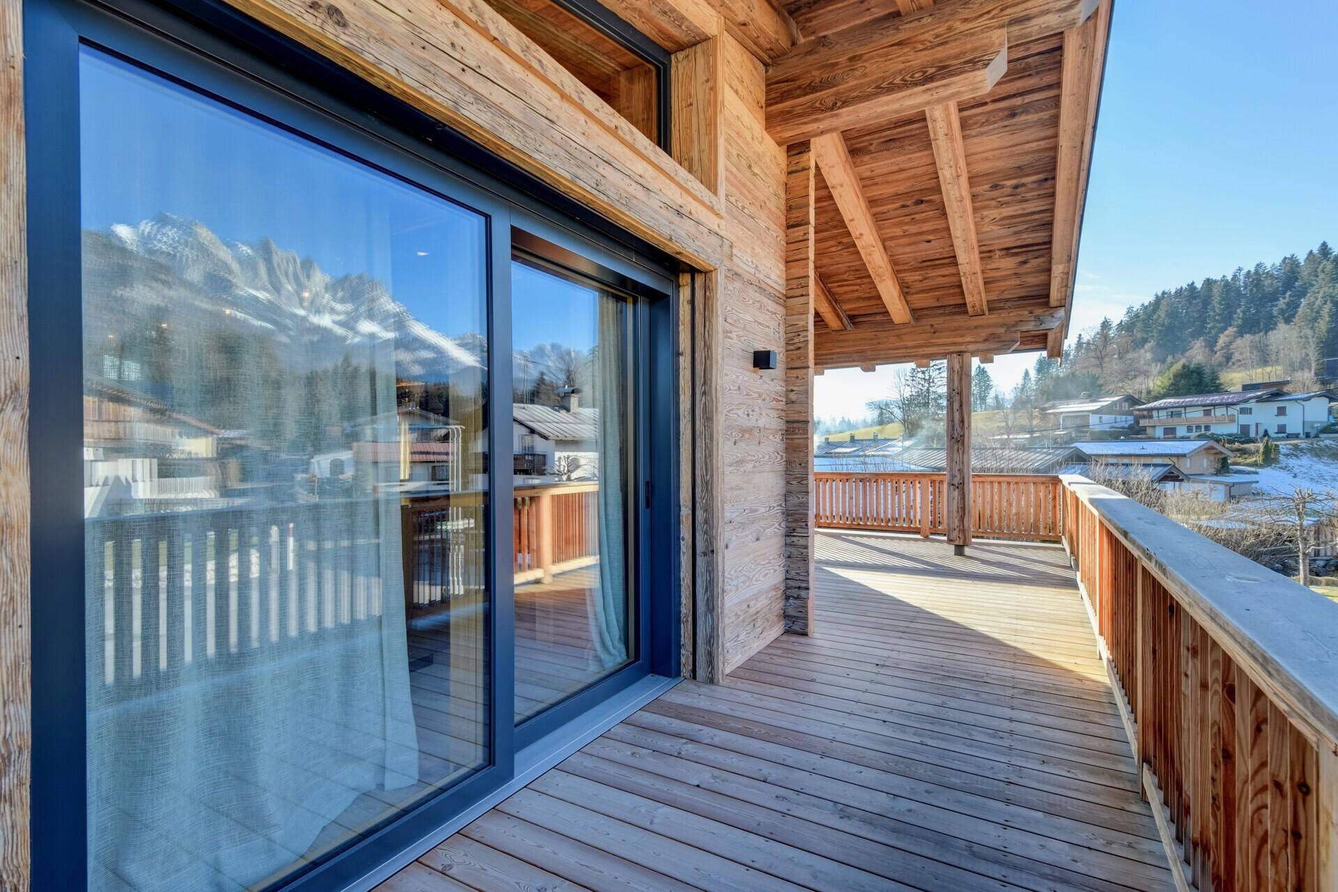 Geräumiger Holzbalkon mit Schiebetüren und Bergblick, ideal für sonnige Tage und frische Luft.