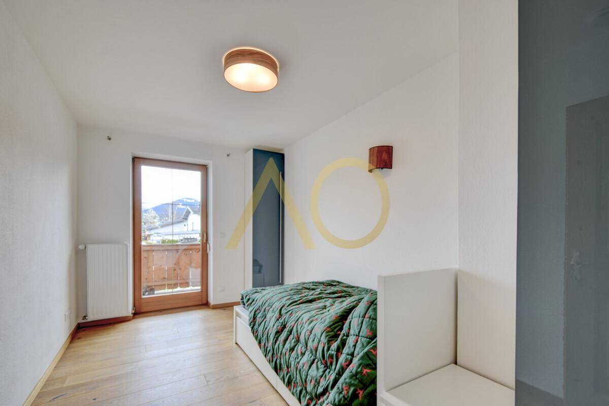 Schlafzimmer mit Holzboden, Zugang zum Balkon und Blick auf die Umgebung.