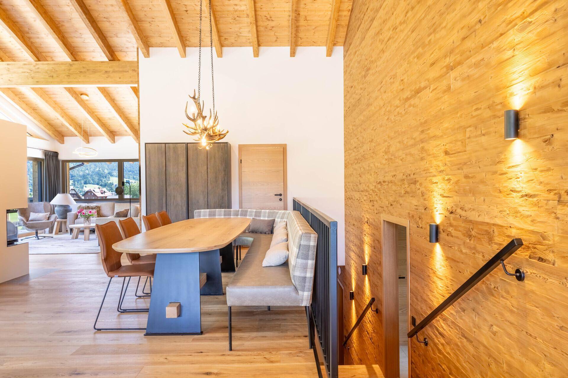 Gemütlicher Essbereich mit Holztisch, Sitzbank und Hirschgeweih-Lampe in alpiner Atmosphäre.
