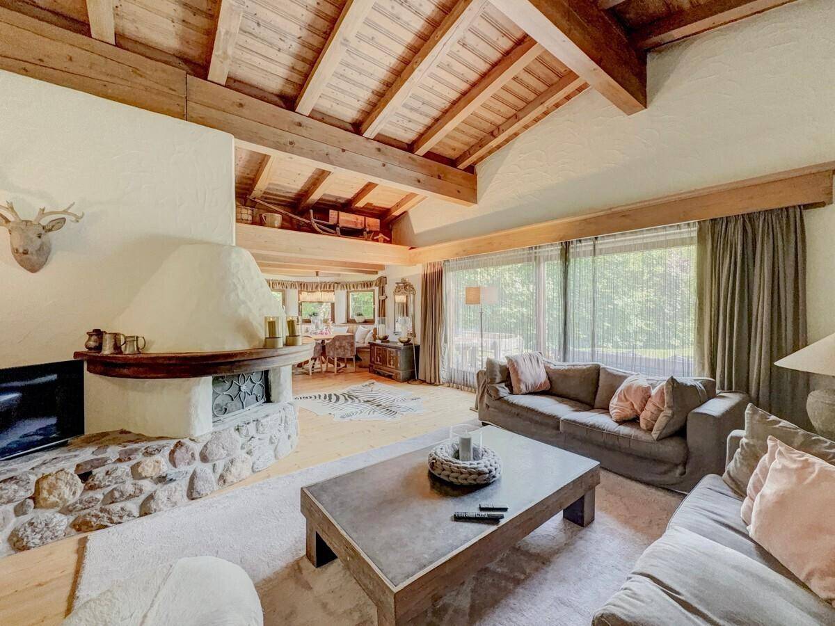 Gemütliches Wohnzimmer mit Kamin, bequemen Sofas und Holzbalkendecke im Landhausstil.