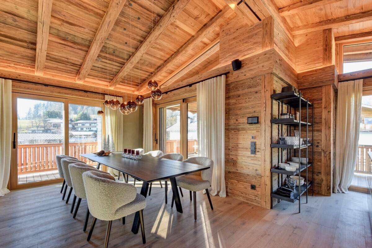 Heller Essbereich mit großem Holztisch, modernen Stühlen und Zugang zum Balkon.