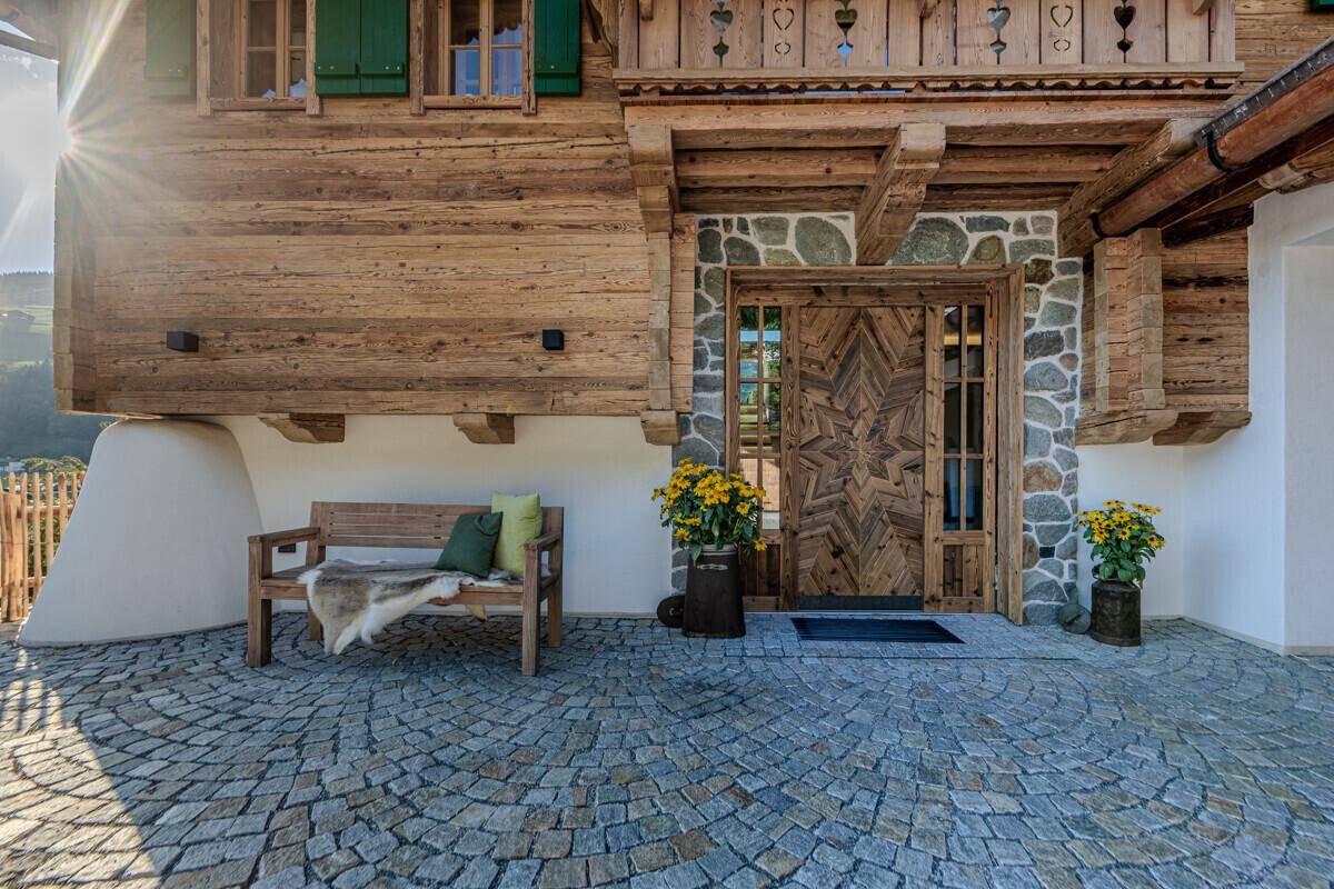 Traditionelles Chalet mit Holzelementen, Steinfassade und kunstvoll geschnitzter Eingangstür.