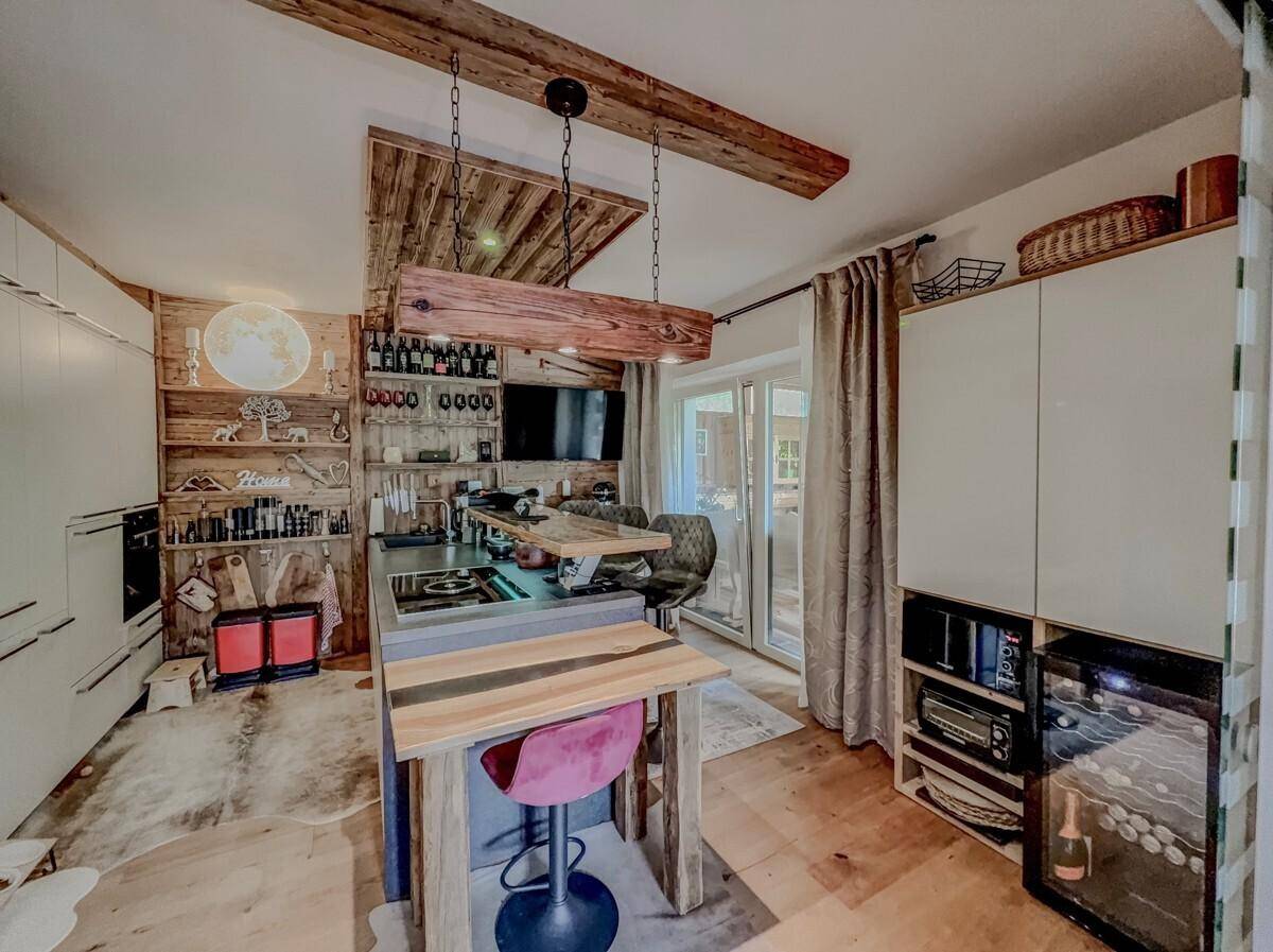 Moderne Küche im Landhausstil mit Kochinsel, Holzelementen und integriertem Weinkühler.