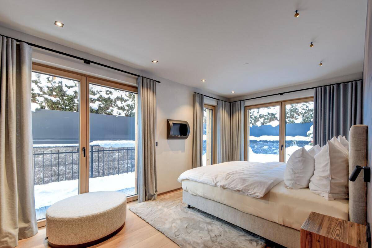 Modernes Schlafzimmer mit großem Bett, bodentiefen Fenstern und Zugang zum Balkon.
