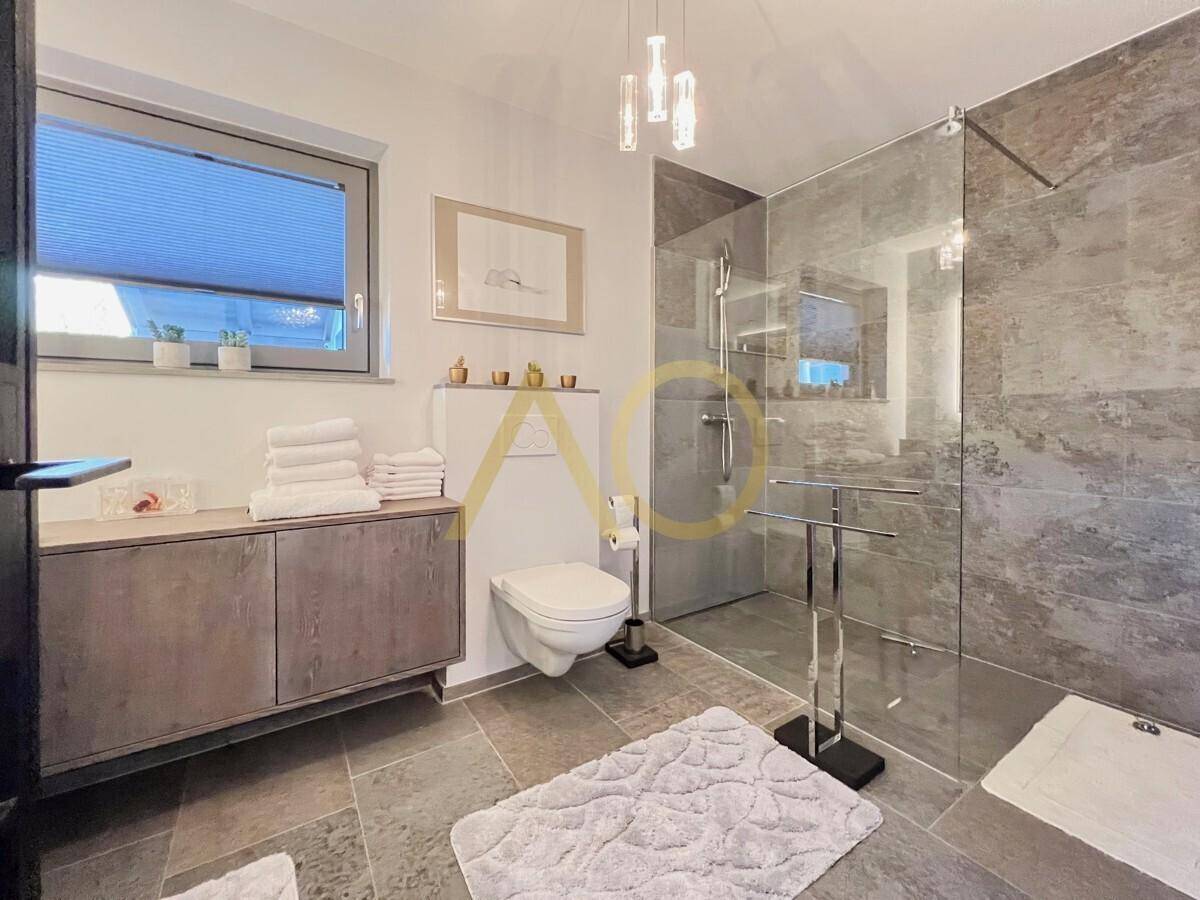 Helles Schlafzimmer mit modernem Bett, offenem Regal und angrenzendem Badezimmer.