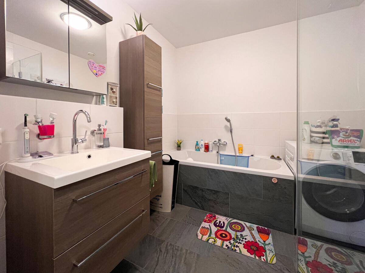 Helles Badezimmer mit großer begehbarer Dusche, modernem Waschtisch und beheiztem Handtuchhalter.