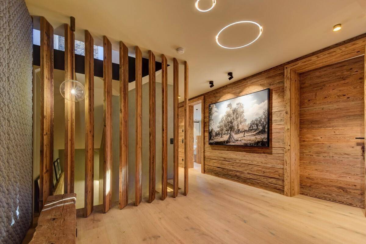 Heller Flur mit Holzlamellen, Kunstwerk und indirekter Beleuchtung.