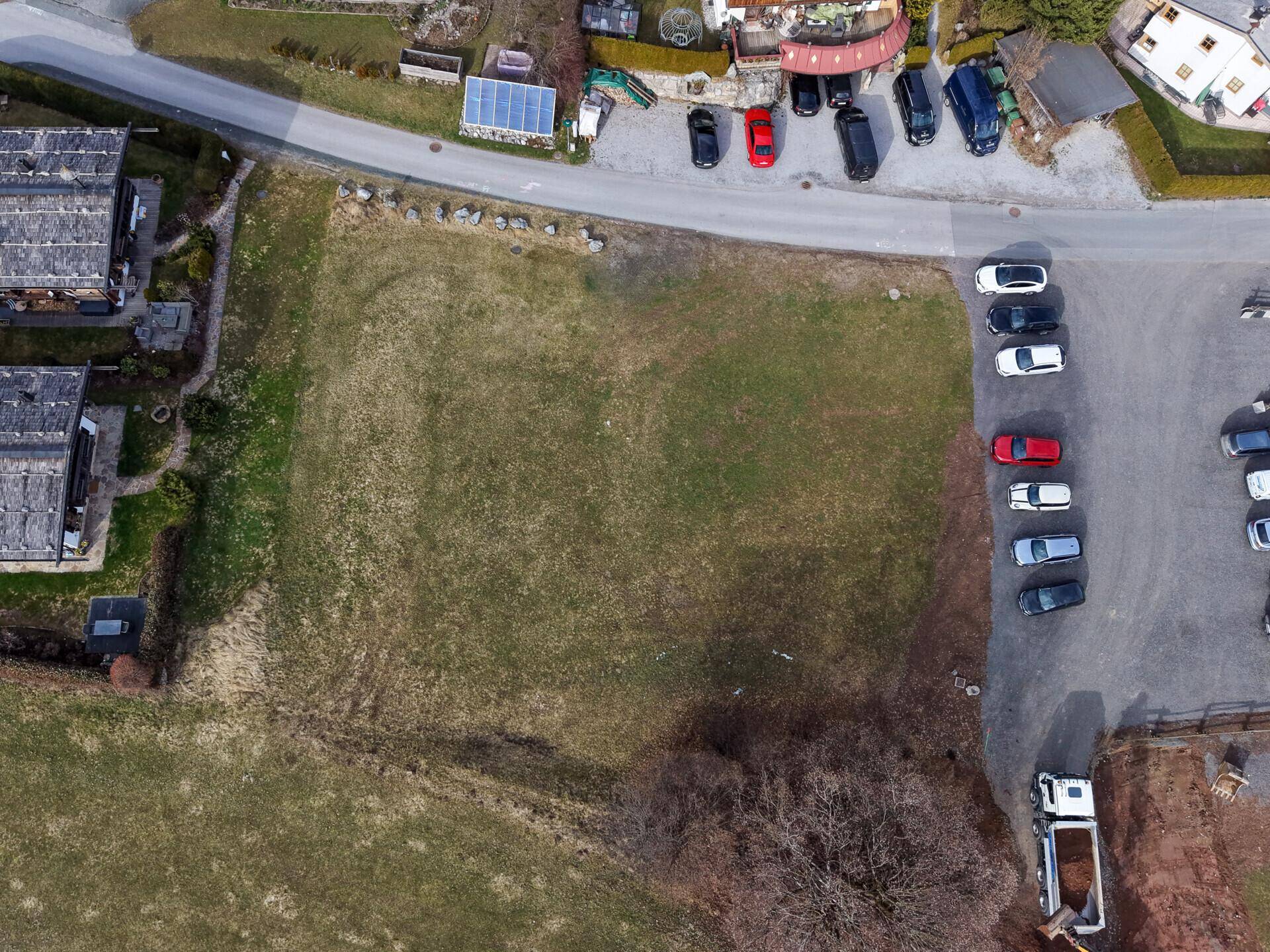 Luftaufnahme eines unbebauten Grundstücks umgeben von Straßen und Parkplätzen in ländlicher Gegend.