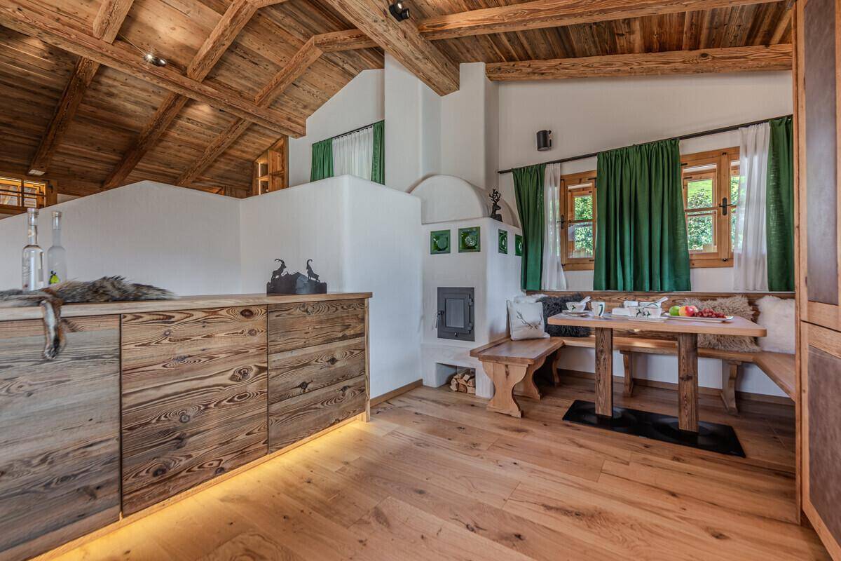 Gemütliche Essecke mit traditionellem Kachelofen, Holztisch und Blick ins Grüne.
