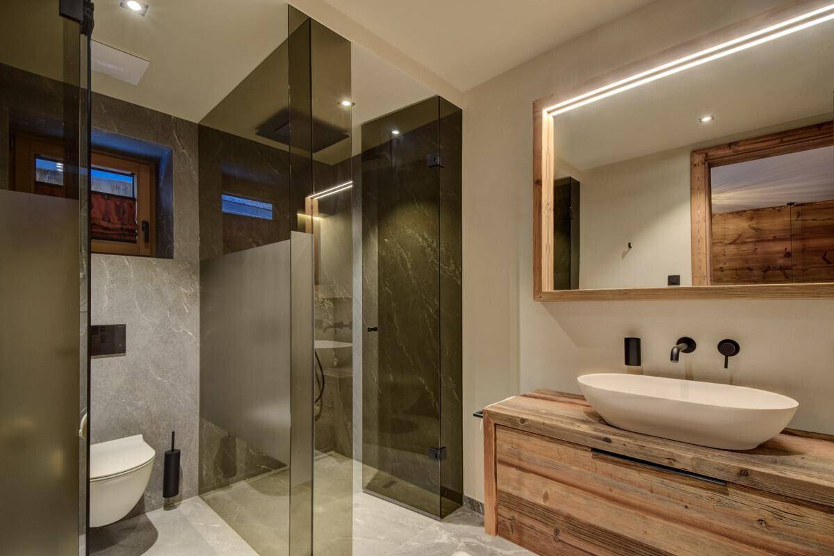 Modernes Badezimmer mit Holzwaschtisch, begehbarer Dusche und Wand-WC.