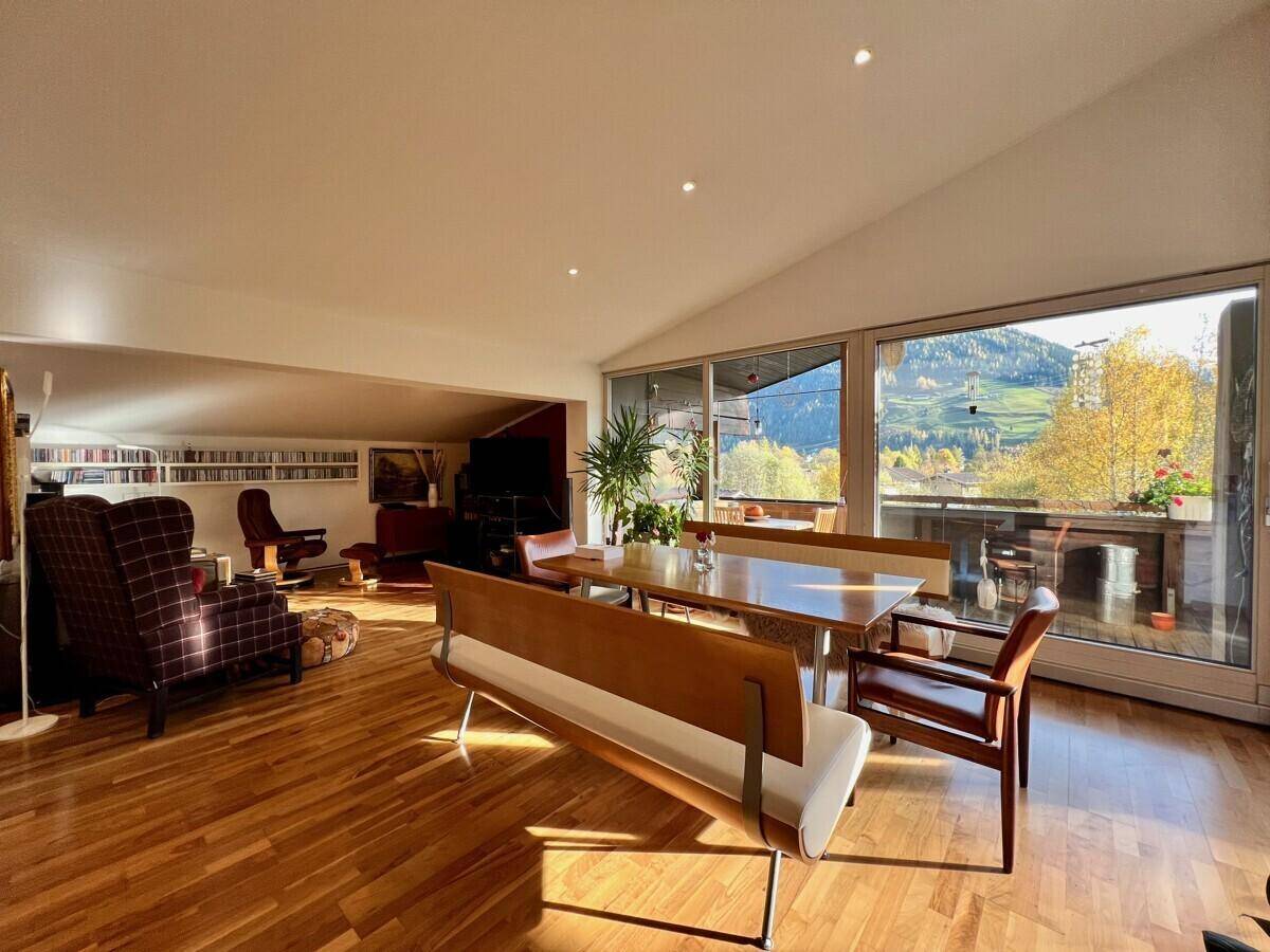 Heller Wohn-Essbereich mit Holzboden, Dachschräge und Zugang zum Balkon mit Bergblick.