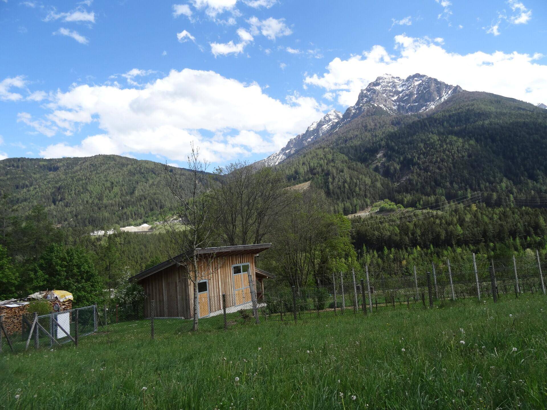 Idyllische Landschaft mit einem kleinen Holzschuppen, grünen Wiesen und majestätischen Bergen.