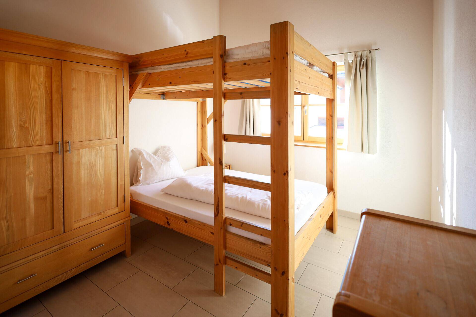 Kinderzimmer mit Etagenbett und großem Holzschrank, ideal für Gäste.