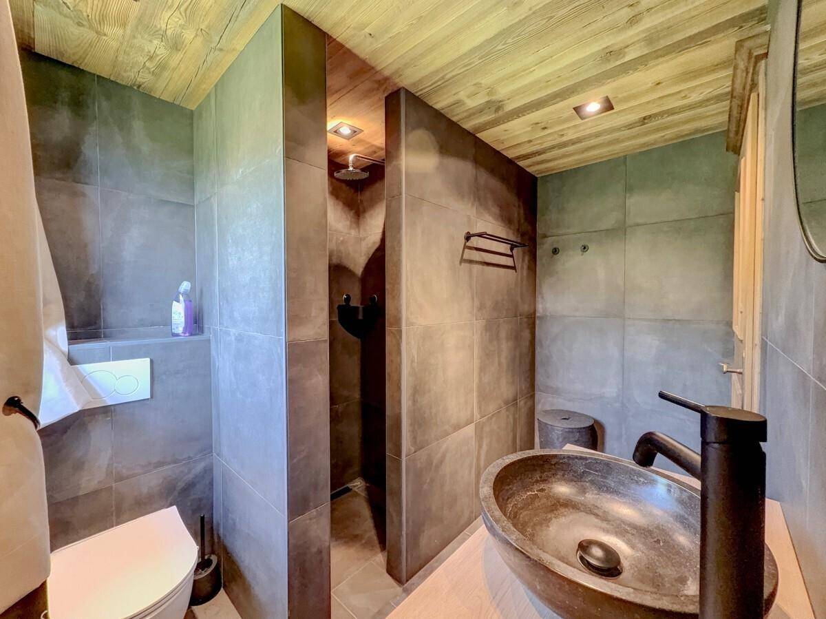 Modernes Badezimmer mit dunklen Fliesen, Doppelwaschtisch und begehbarer Dusche.