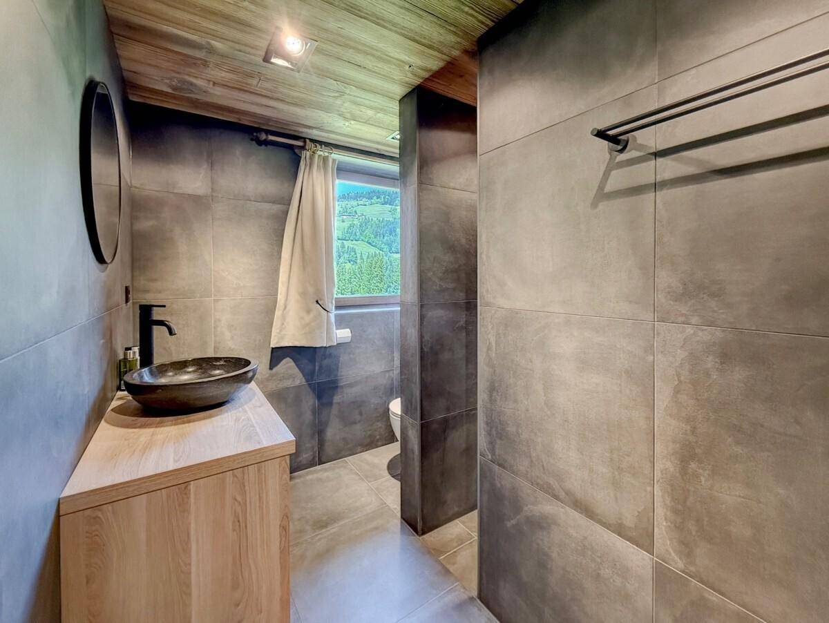 Modernes Badezimmer mit dunklen Fliesen, Waschtisch und begehbarer Dusche.