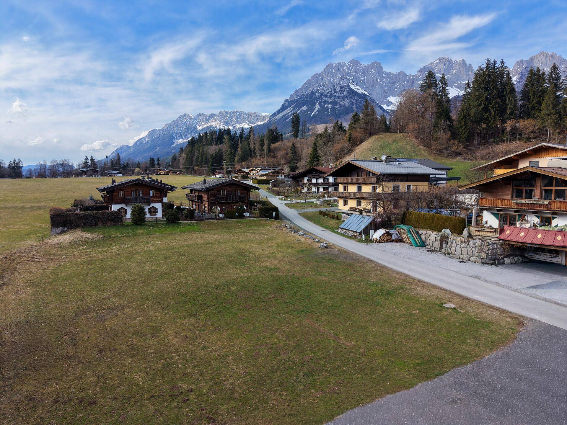 Panoramablick auf eine ländliche Siedlung mit traditionellen Häusern vor einer beeindruckenden Bergkulisse.