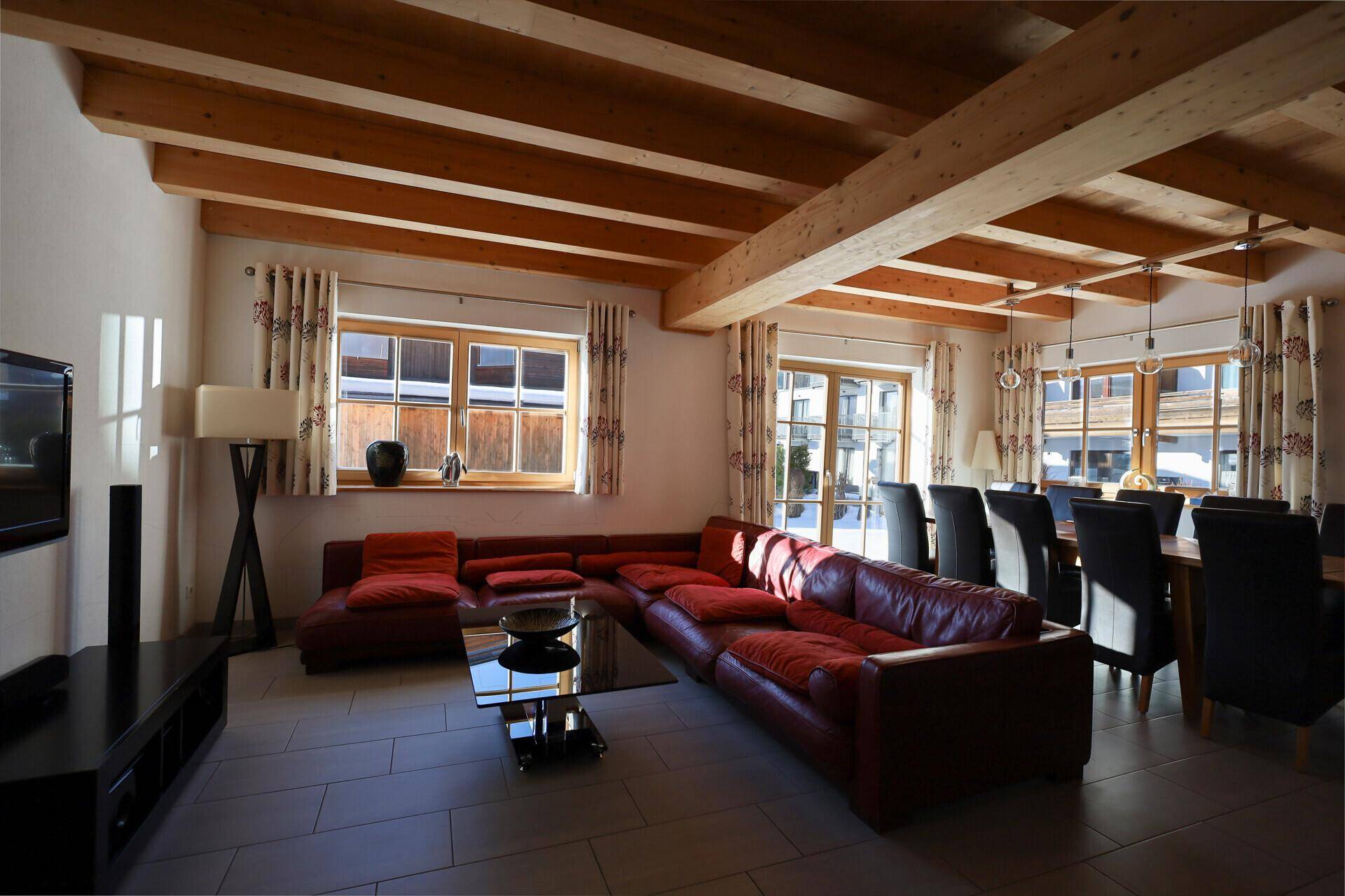 Heller Wohnbereich mit roter Ledercouch, Couchtisch und Blick auf den Essbereich.