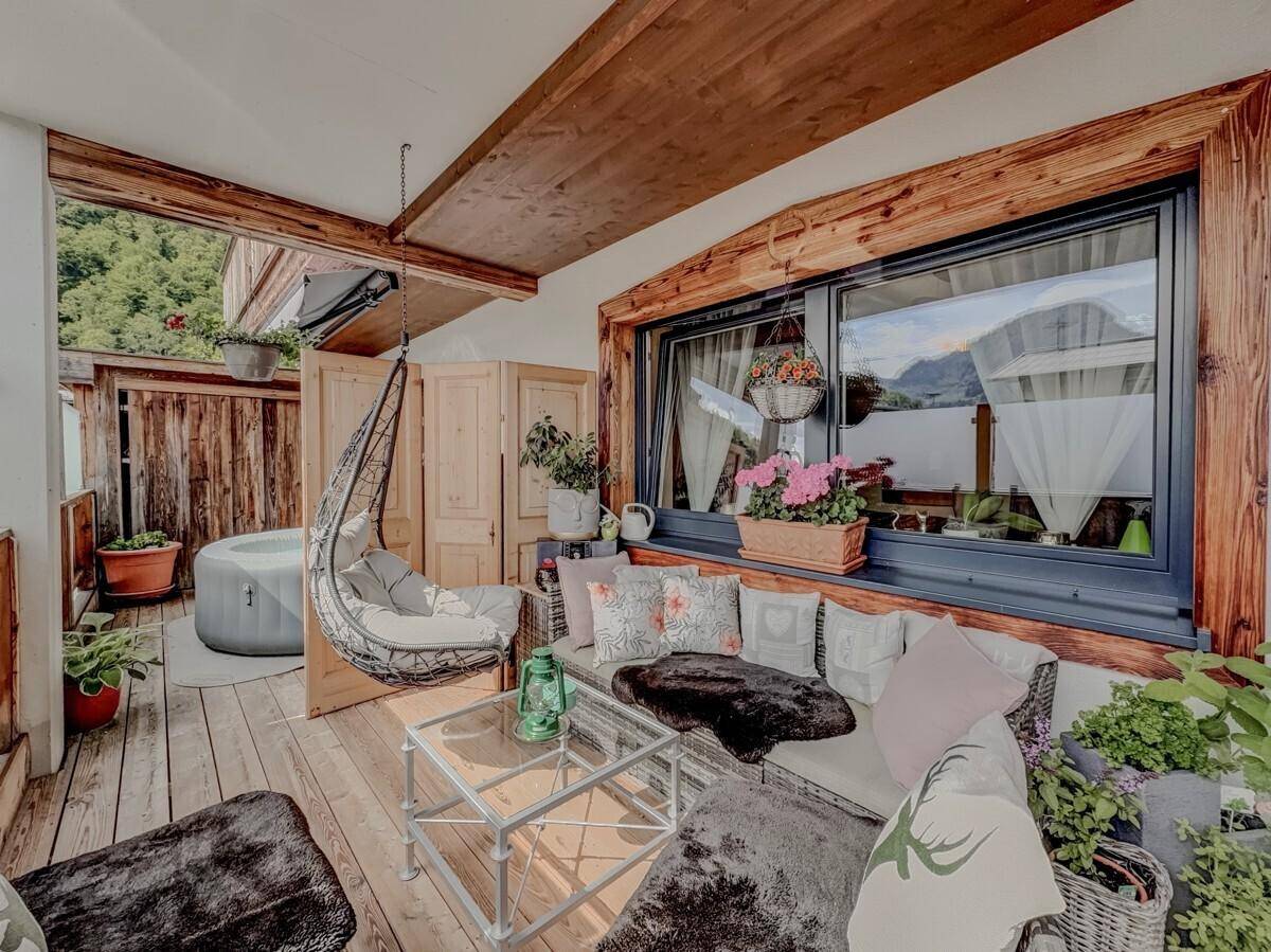 Überdachte Loggia mit bequemen Loungemöbeln, Hängesessel und Blick auf die Berge.