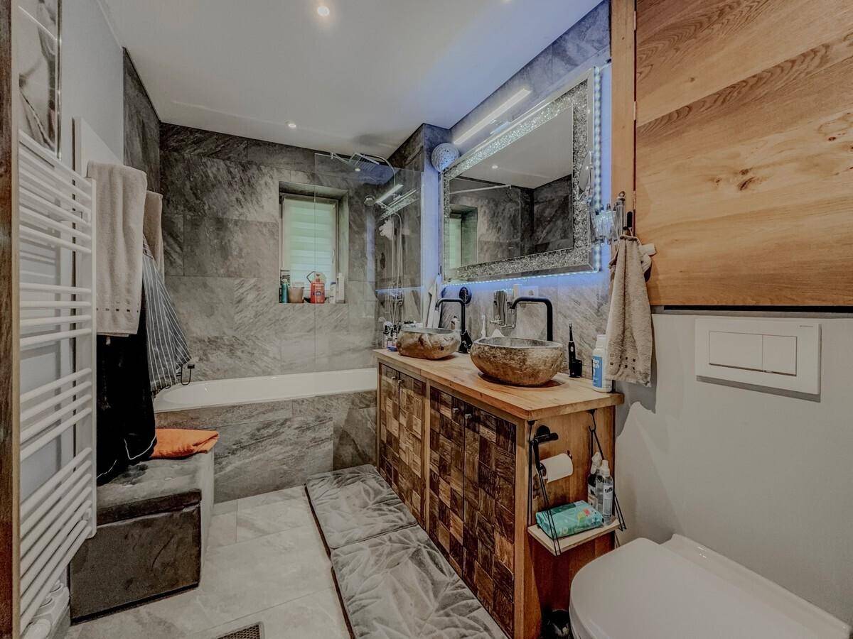 Modernes Badezimmer mit Doppelwaschbecken, Badewanne und grauen Fliesen.