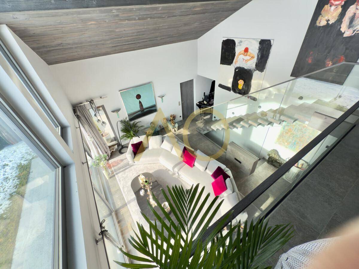 Blick von der Galerie auf den Wohnbereich mit moderner Einrichtung und hohen Decken.