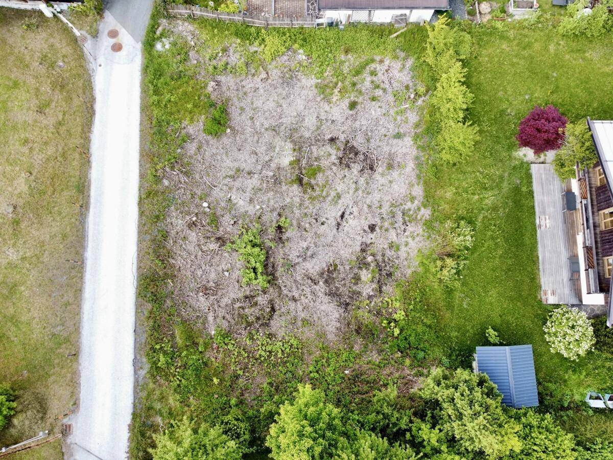 Luftaufnahme eines gerodeten Grundstücks, umgeben von grünen Wiesen und benachbarten Häusern.